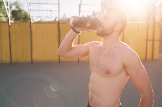 Imagen de un joven atlético después del entrenamiento. guapo joven musculoso bebe una proteína. Sportasman atlético atractivo sin camisa bebiendo batido de nutrición deportiva de blender