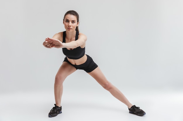 Imagen de una joven y bella mujer de fitness deporte hacer ejercicios aislados sobre pared gris.