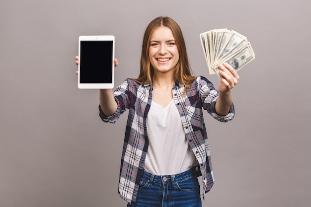 Foto imagen de joven excitada. mirando la cámara que muestra la pantalla de la tableta con dinero.