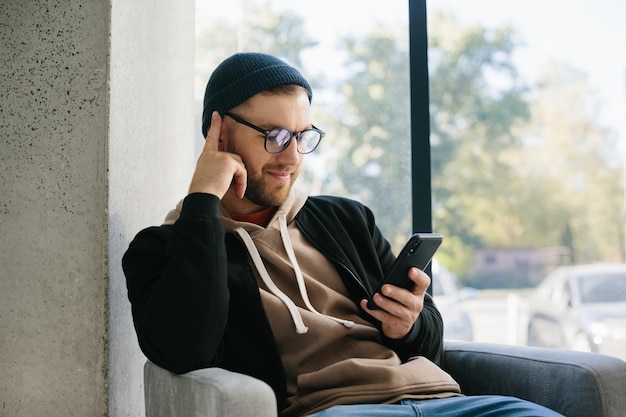 Imagen de un joven feliz sosteniendo su celular en las manos y charlando