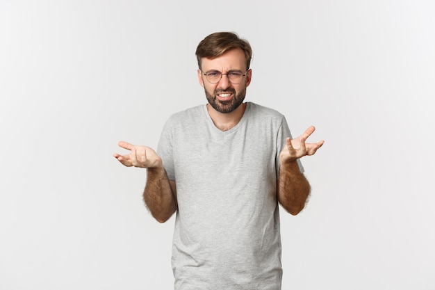 Imagen de un joven frustrado con gafas y camiseta gris