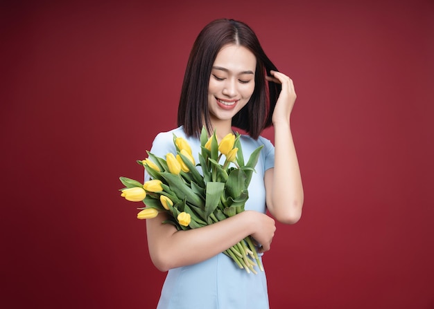 imagen, de, joven, mujer asiática, tenencia, tulipanes, flores, en, plano de fondo