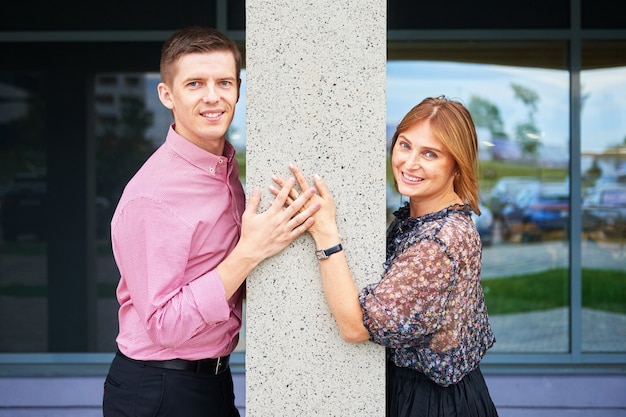 Foto imagen de una joven pareja cogidos de la mano alrededor de una columna de hormigón