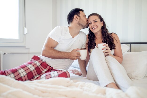 Imagen de la joven pareja tomando café en la cama