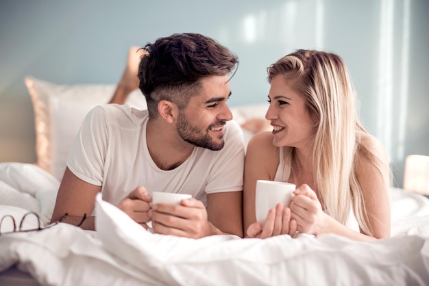 Imagen de la joven pareja tomando café en la cama