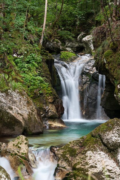 Imagen de larga exposición de una hermosa corriente de agua cayendo de las rocas cubiertas de musgo