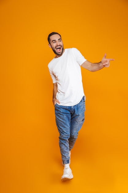 Foto imagen de longitud completa de hombre feliz de 30 años en camiseta y jeans sonriendo mientras camina, aislado