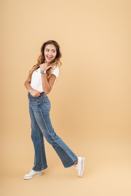 Imagen de longitud completa de mujer caucásica sonriendo y señalando con el dedo en copyspace aislado