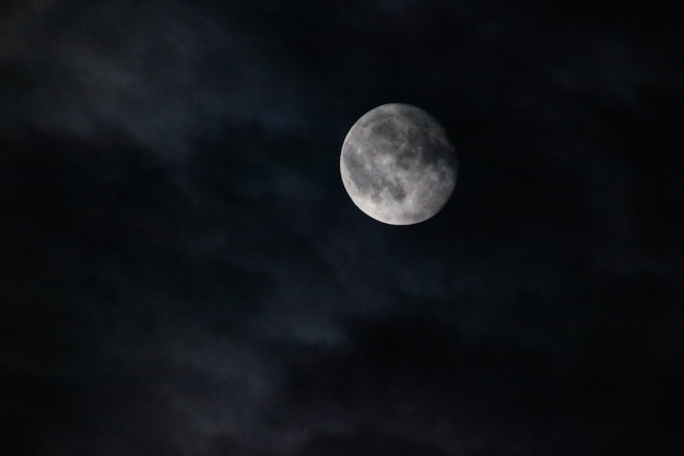 Imagen de luna llena con un ominoso cielo oscuro y espeluznantes nubes tenues