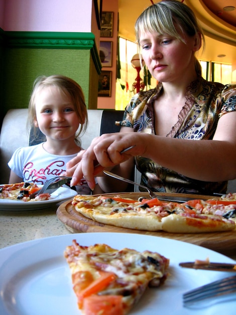 Imagen de madre e hija comiendo en una pizzería