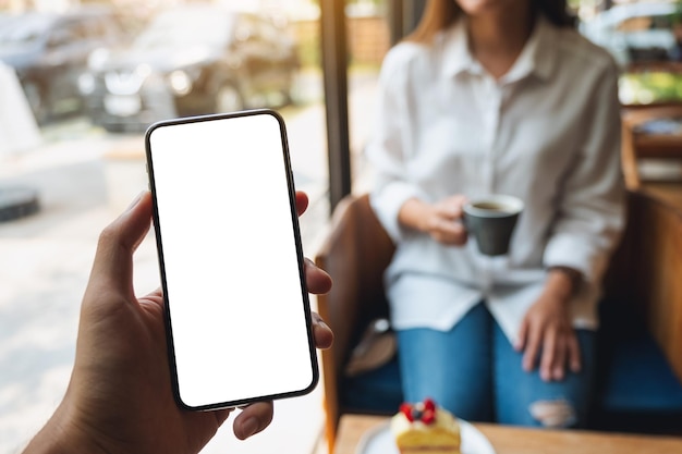 Imagen de una maqueta de un hombre que sostiene un teléfono móvil con una pantalla blanca en blanco con una mujer en segundo plano