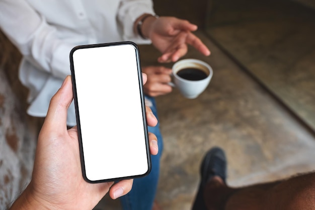 Imagen de una maqueta de un hombre sosteniendo y mostrando un teléfono móvil con una pantalla de escritorio en blanco a su amigo mientras conversan juntos