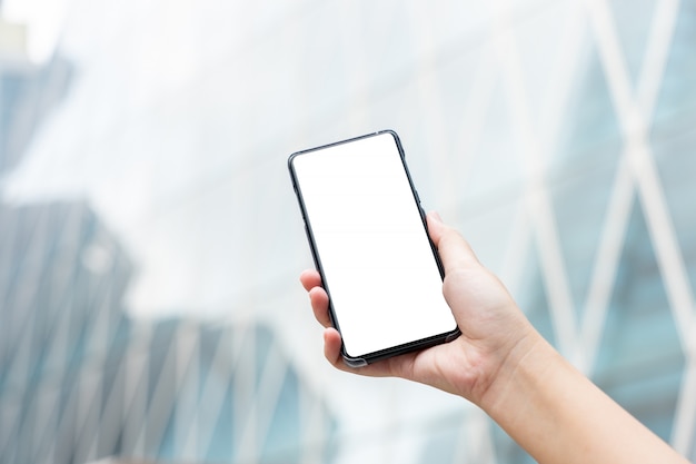 La imagen de la maqueta de la mano de la mujer que sostenía smartphones móviles aisló la pantalla blanca