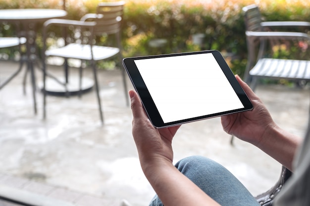 Imagen de maqueta de manos de mujer sosteniendo tablet pc negro con pantalla de escritorio en blanco blanco en café