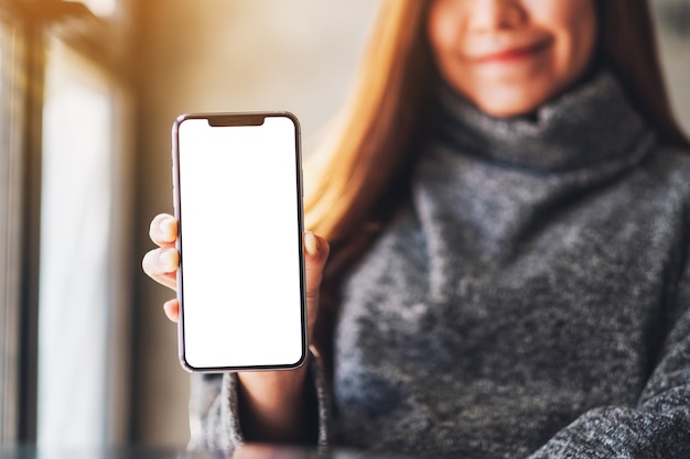 Imagen de maqueta de una mujer asiática sosteniendo y mostrando un teléfono móvil negro con pantalla blanca en blanco