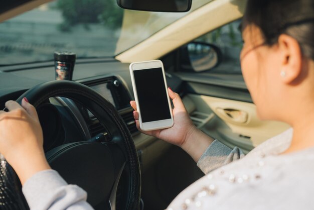 Imagen de maqueta de mujer conductora con smartphone con pantalla en blanco en un coche.