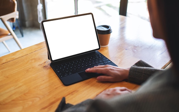 Imagen de maqueta de una mujer de negocios usando y tocando en el panel táctil de la tableta con pantalla de escritorio en blanco como computadora PC con taza de café sobre la mesa