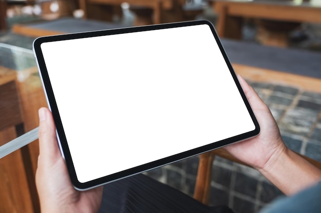 Imagen de maqueta de una mujer que sostiene una tableta digital con una pantalla de escritorio en blanco en la cafetería