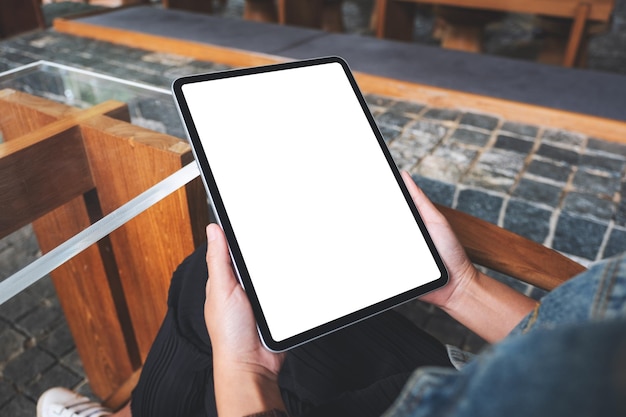 Imagen de maqueta de una mujer que sostiene una tableta digital con una pantalla de escritorio en blanco en la cafetería