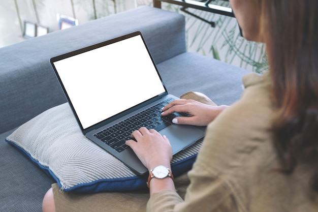 Imagen de maqueta de una mujer que usa y escribe en el teclado de una computadora portátil con pantalla en blanco mientras está sentada en la sala de estar