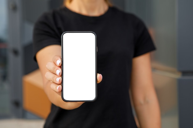 Imagen de maqueta. Mujer señalando con el dedo a un teléfono móvil con pantalla en blanco en blanco
