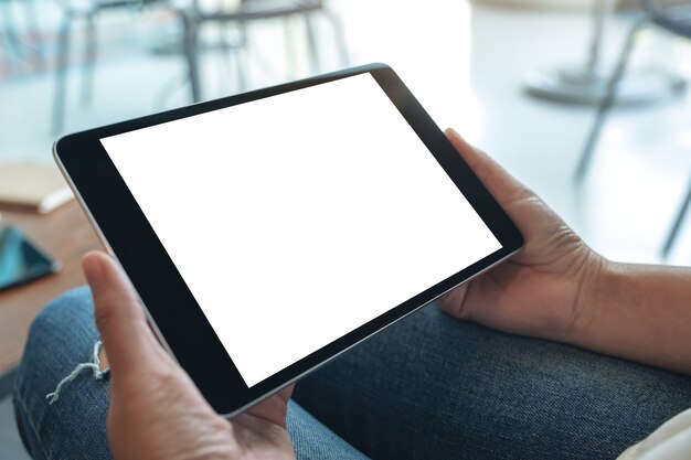Imagen de maqueta de una mujer sentada y sosteniendo una tablet pc negra con una pantalla de escritorio blanca en blanco horizontalmente