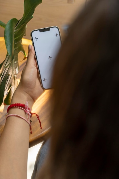 Imagen de maqueta de una mujer sosteniendo y mostrando teléfono móvil negro con pantalla en blanco