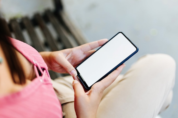 Foto imagen de maqueta de mujer sosteniendo un teléfono inteligente con pantalla en blanco al aire libre