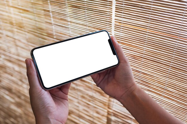 Imagen de maqueta de una mujer sosteniendo un teléfono móvil con una pantalla de escritorio en blanco en blanco