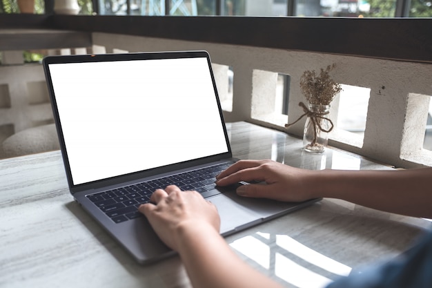 Foto imagen de maqueta de una mujer usando y escribiendo en la computadora portátil con pantalla en blanco en el café moderno