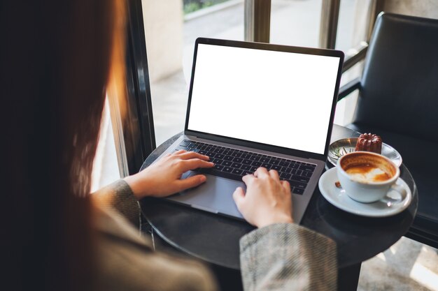 Imagen de maqueta de una mujer usando y escribiendo en una computadora portátil con pantalla de escritorio en blanco en el café