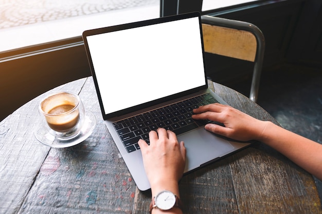 Imagen de maqueta de una mujer usando y escribiendo en el teclado de una computadora portátil con pantalla de escritorio en blanco en la mesa de madera