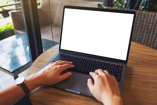 Foto imagen de maqueta de una mujer usando y escribiendo en el teclado de la computadora portátil con pantalla de escritorio en blanco en la mesa de madera