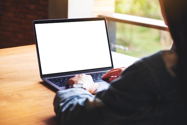 Imagen de maqueta de una mujer usando y escribiendo en el teclado de la computadora portátil con pantalla de escritorio en blanco en la mesa de madera