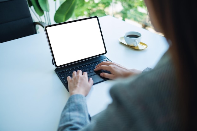 Imagen de maqueta de una mujer usando y escribiendo en el teclado de una tableta con una pantalla de escritorio en blanco como una computadora en la oficina