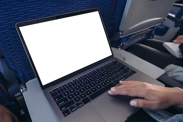 Imagen de maqueta de una mujer usando y tocando el panel táctil de la computadora portátil con pantalla de escritorio en blanco mientras está sentada en la cabina