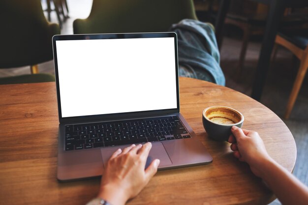 Imagen de maqueta de una mujer usando y tocando en el panel táctil de la computadora portátil con pantalla de escritorio en blanco mientras toma café