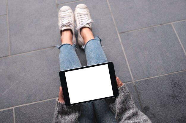 Imagen de maqueta de vista superior de manos de mujer sosteniendo y usando tablet pc negro