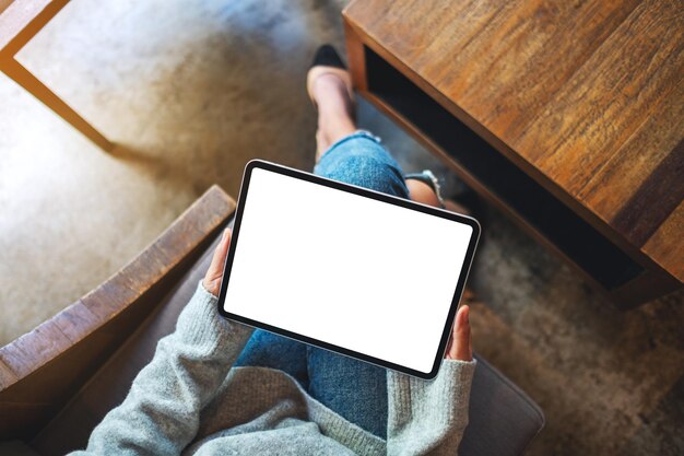 Imagen de maqueta de vista superior de una mujer de negocios que sostiene una tableta digital con una pantalla de escritorio blanca en blanco