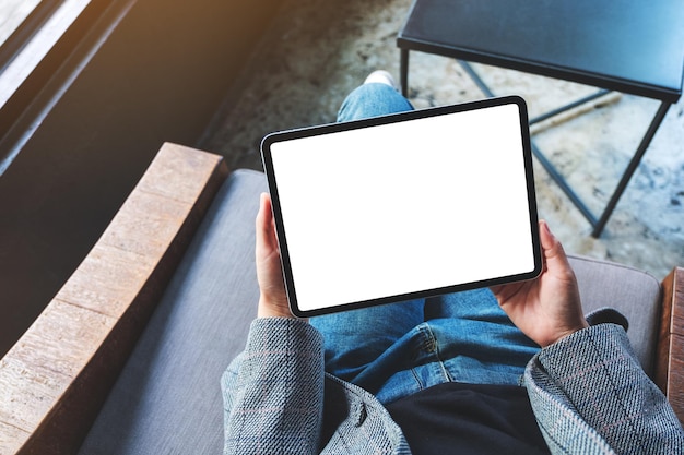 Imagen de maqueta de vista superior de una mujer sosteniendo tablet pc negro con pantalla de escritorio en blanco en blanco