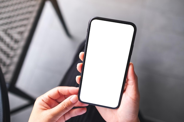 Imagen de maqueta de vista superior de una mujer sosteniendo un teléfono móvil con pantalla de escritorio en blanco en blanco