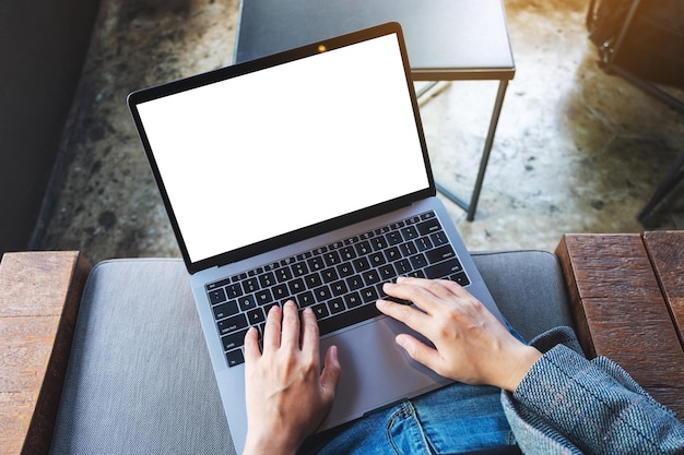 Imagen de maqueta de vista superior de una mujer usando y escribiendo en una computadora portátil con pantalla de escritorio en blanco en blanco