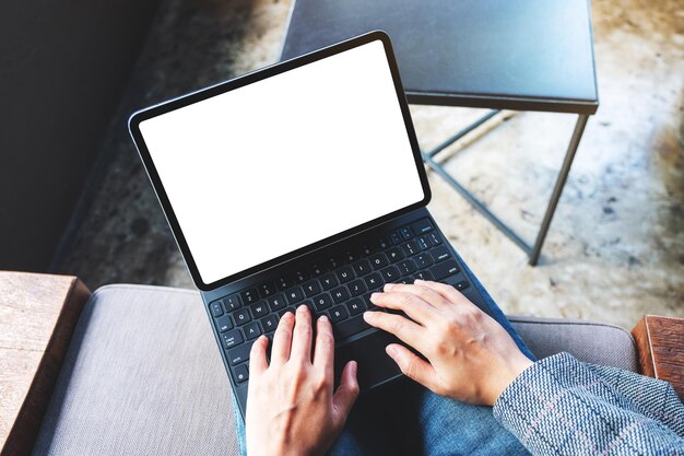 Imagen de maqueta de vista superior de una mujer usando y escribiendo en el teclado de la tableta con pantalla de escritorio en blanco como una computadora pc