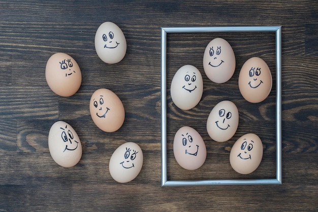 Imagen marco dorado y muchos huevos divertidos sonriendo sobre fondo de pared de madera oscura Huevos emoción familiar cara retrato Concepto comida divertida