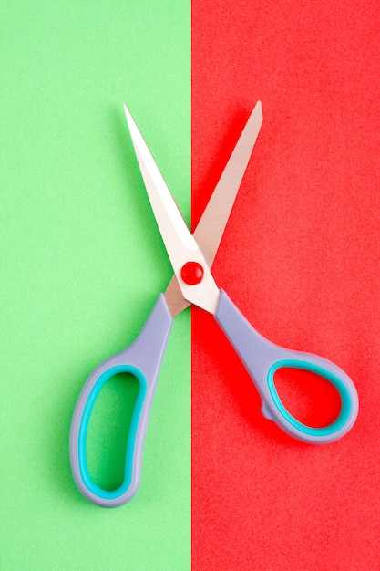 Imagen minimalista de tijeras sobre fondo rojo y verde.