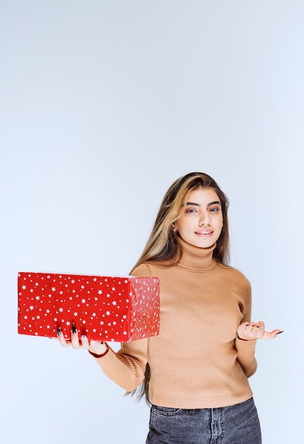 Imagen de un modelo de mujer atractiva sosteniendo un regalo rojo.