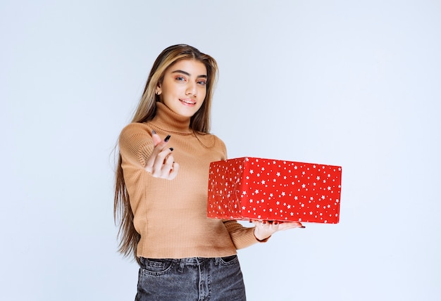 Imagen de un modelo de mujer atractiva sosteniendo un regalo rojo.