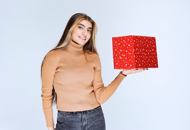 Imagen de un modelo de mujer atractiva sosteniendo un regalo rojo.