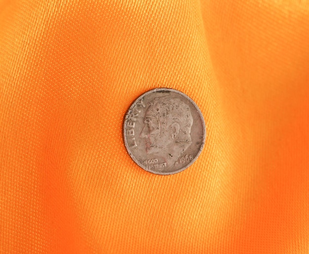 Imagen de una moneda antigua sobre tela amarilla.