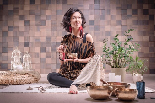 Imagen de una mujer adulta en lugar de yoga. Tocando cuencos tibetanos. El concepto de yoga y prácticas espirituales. Técnica mixta